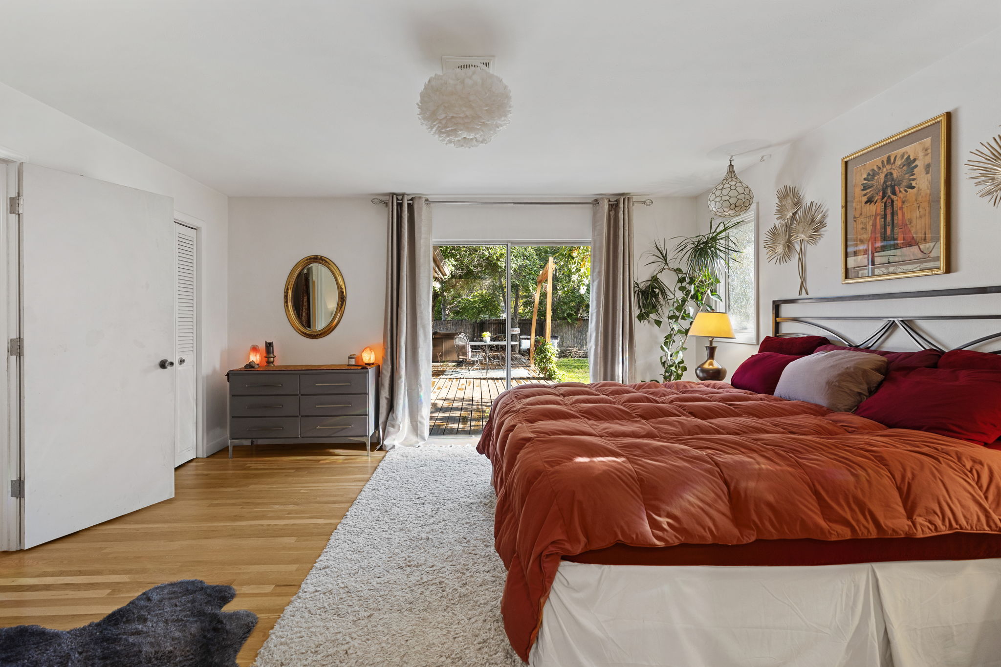 Spacious primary bedroom with hardwood floors, natural light, and sliding glass door access to the private back deck