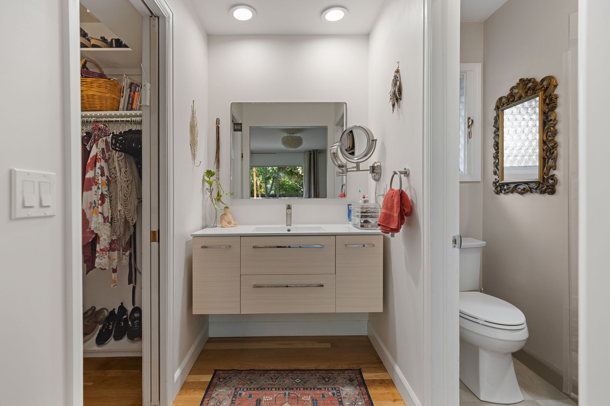 Primary ensuite vanity with modern floating cabinetry, double-light mirrors, and a walk-in closet