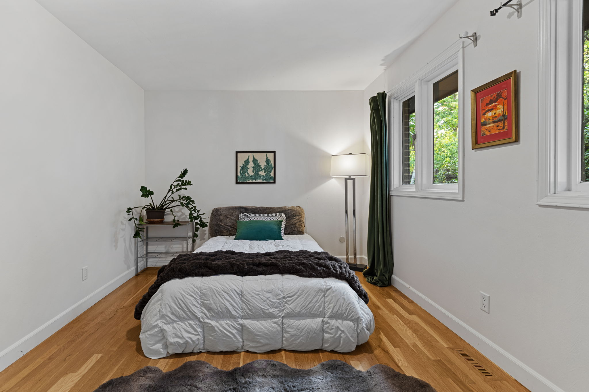 Comfortable 2nd bedroom featuring rich wood flooring, natural light, and clean white walls
