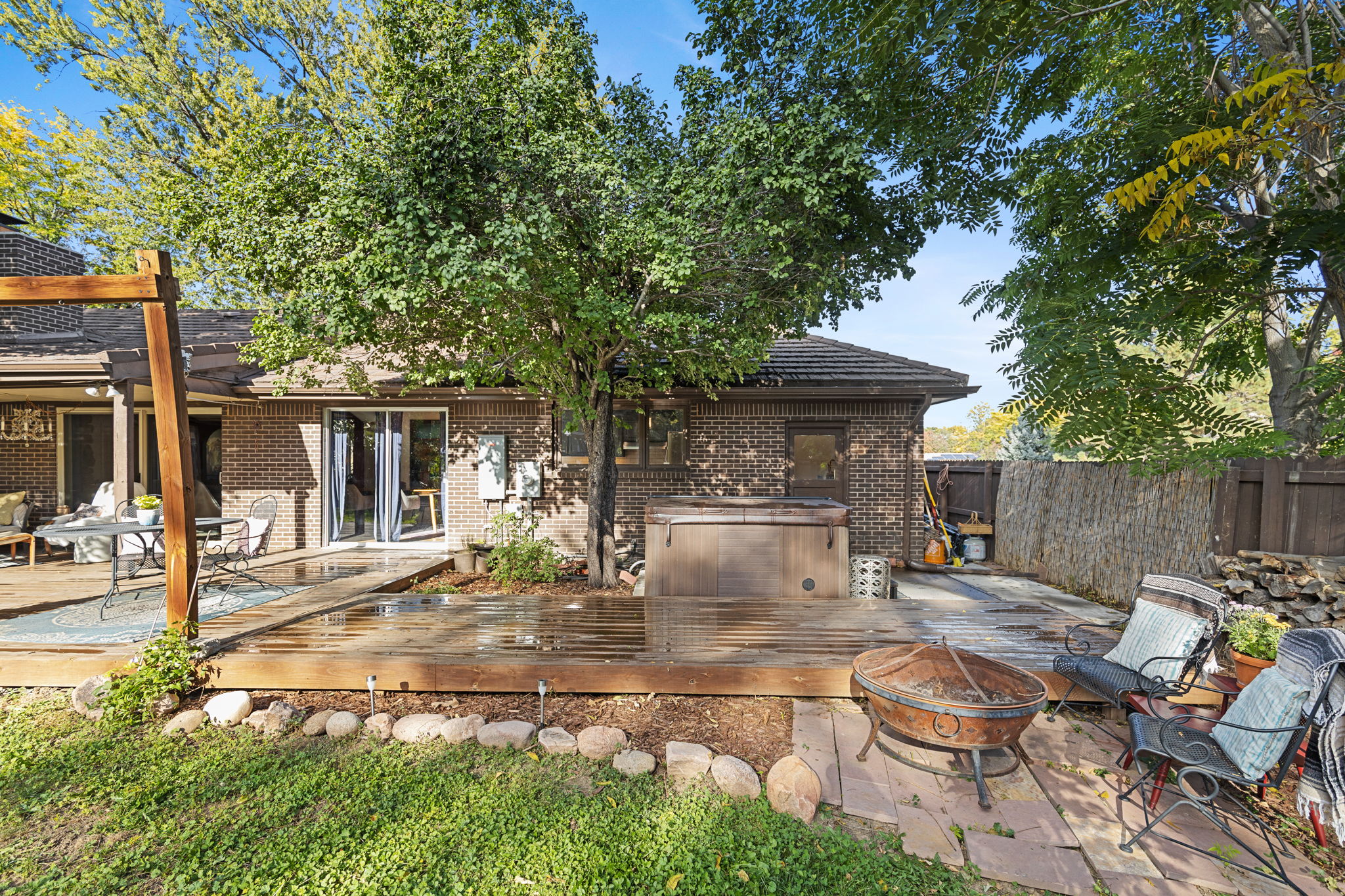 Spacious back deck featuring a premium hot tub, seating area, and mature trees