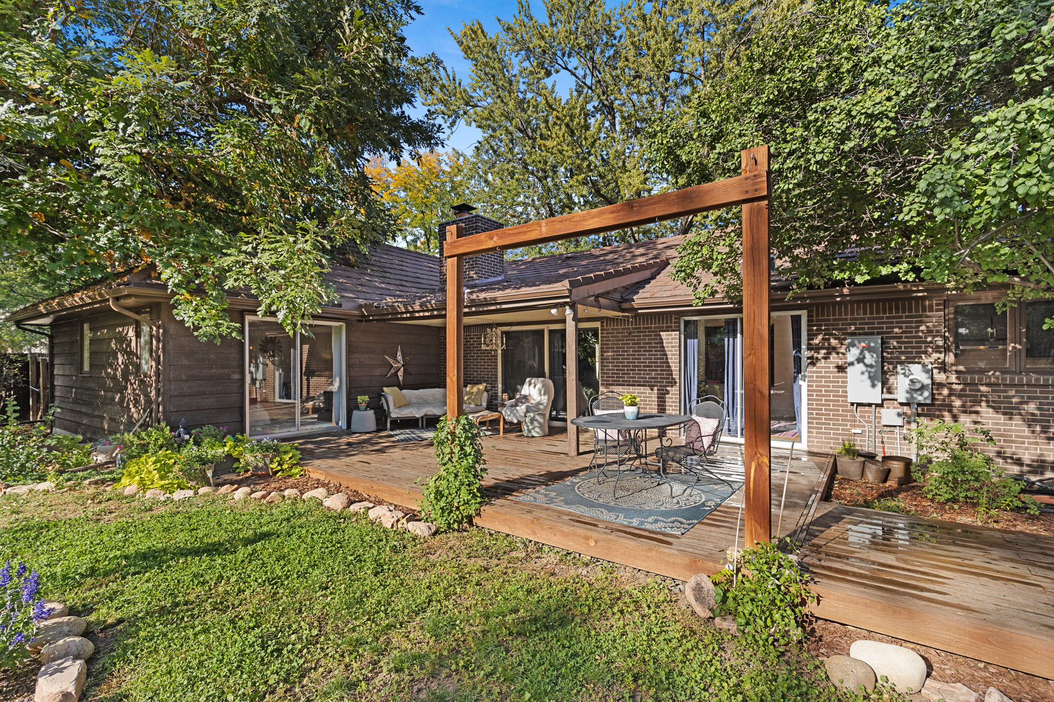 Generous deck with pergola framing, patio seating, and sliding glass door access to the main living areas