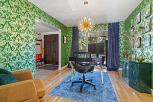Main floor office featuring bold green wallpaper with gold foil accents, hardwood floors, and great natural light