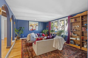 Sitting room with rich blue walls, built-in shelving, and new hardwood flooring throughout the main level