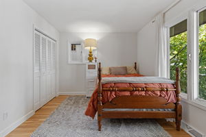 Bright 3rd bedroom with hardwood floors, large sunlit windows, and plenty of closet space