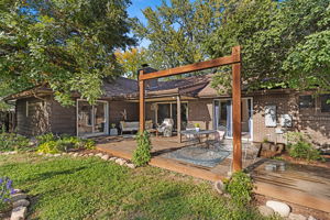 Generous deck with pergola framing, patio seating, and sliding glass door access to the main living areas