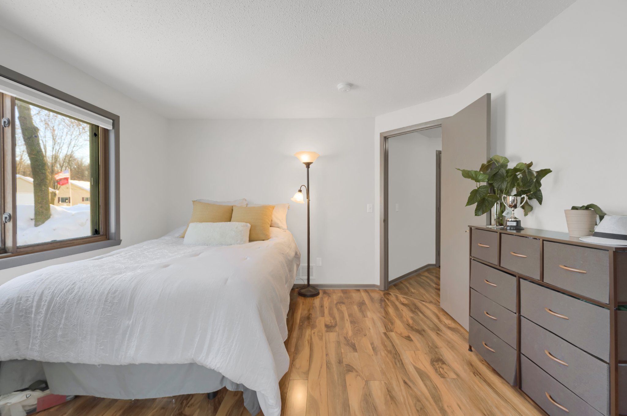 The guest bedroom boasts natural light and ample space and features luxury vinyl tile flooring, which can be found throughout the home.