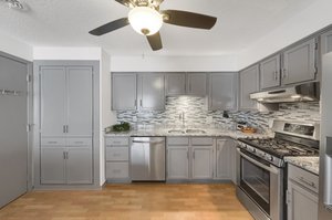 The kitchen was remodeled in 2016, featuring enameled gray cabinets, granite countertops, stainless steel appliances, lighting and fixtures, and a mosaic backsplash.