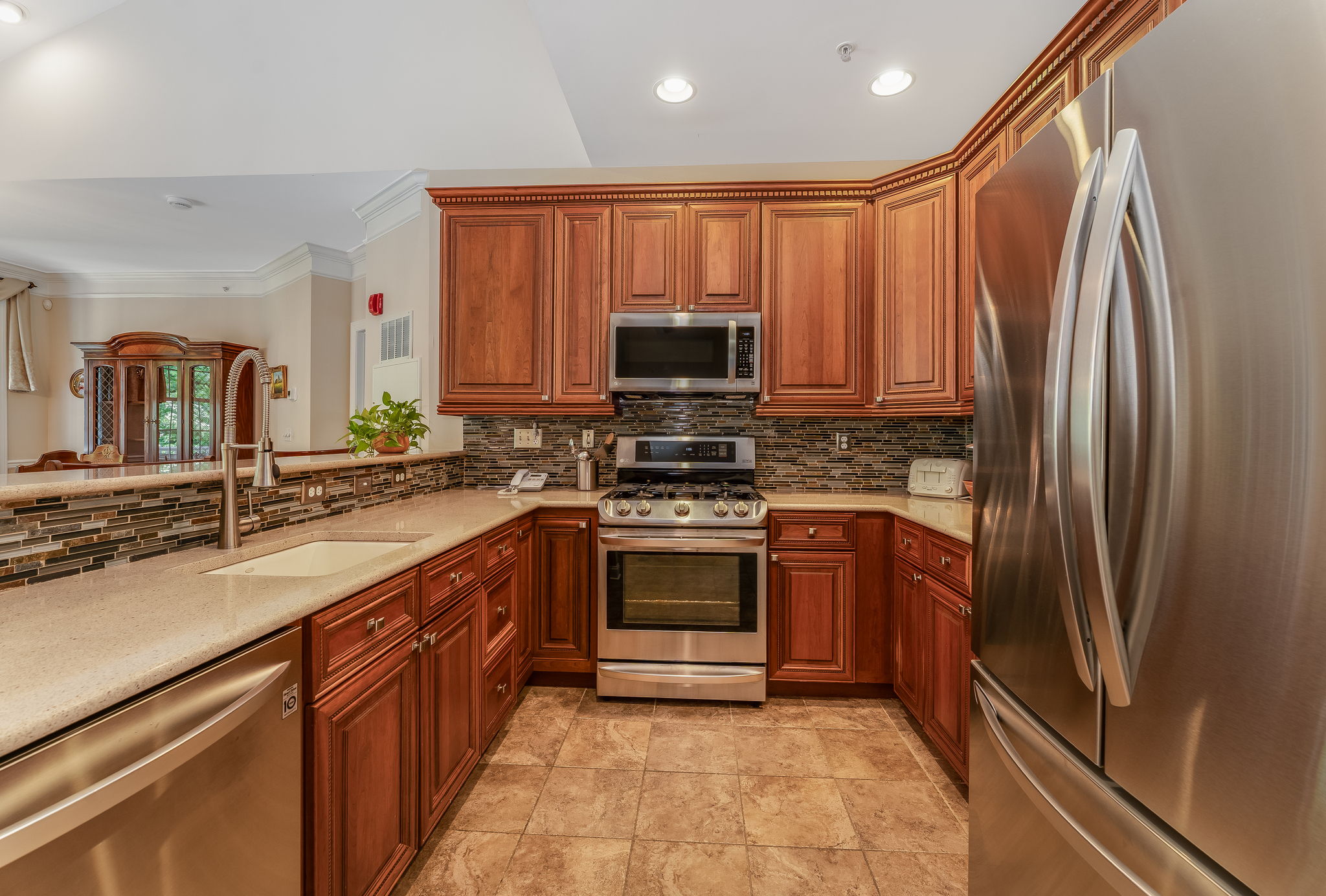 The kitchen features LG stainless steel appliances, abundant 42-inch wood cabinetry, granite countertops, a stacked mosaic backsplash, and ceramic tile floor.