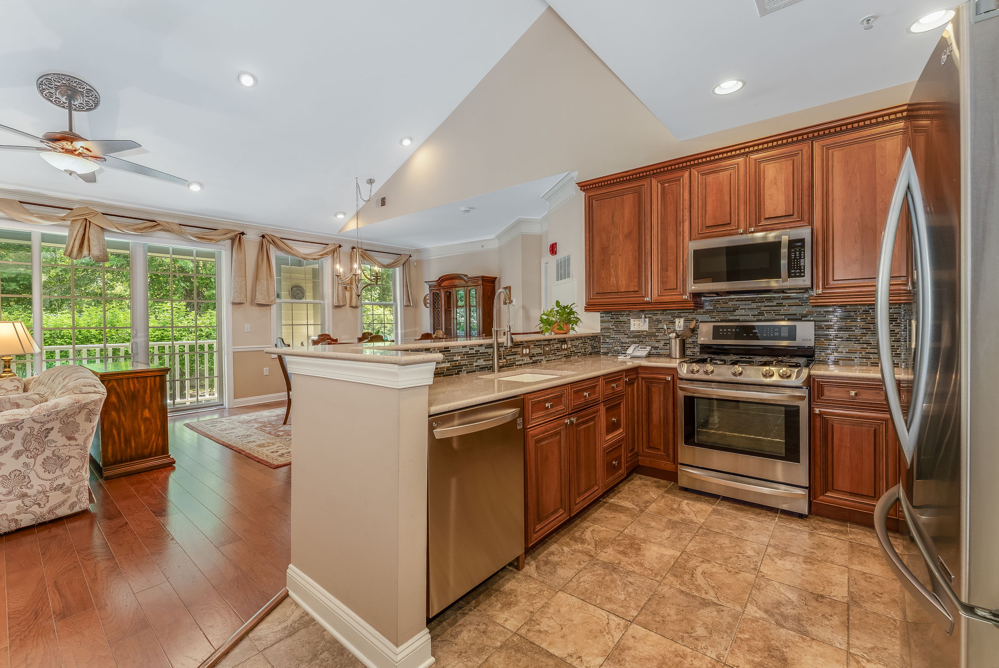 The kitchen features LG stainless steel appliances, abundant 42-inch wood cabinetry, granite countertops, a stacked mosaic backsplash, and ceramic tile floor.