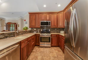 The kitchen features LG stainless steel appliances, abundant 42-inch wood cabinetry, granite countertops, a stacked mosaic backsplash, and ceramic tile floor.