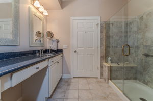 Master Bath The ensuite bath features double sinks and a make-up counter in a white vanity, and a shower in tile surround with bench seating and frameless glass door.