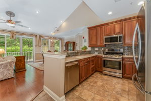The kitchen features LG stainless steel appliances, abundant 42-inch wood cabinetry, granite countertops, a stacked mosaic backsplash, and ceramic tile floor.