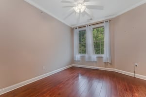 Furniture Removed/Virtually Staged Bedroom 2 features hardwood flooring and walk-in closet. The closet was converted into a pantry, with built-in shelving for organized storage.