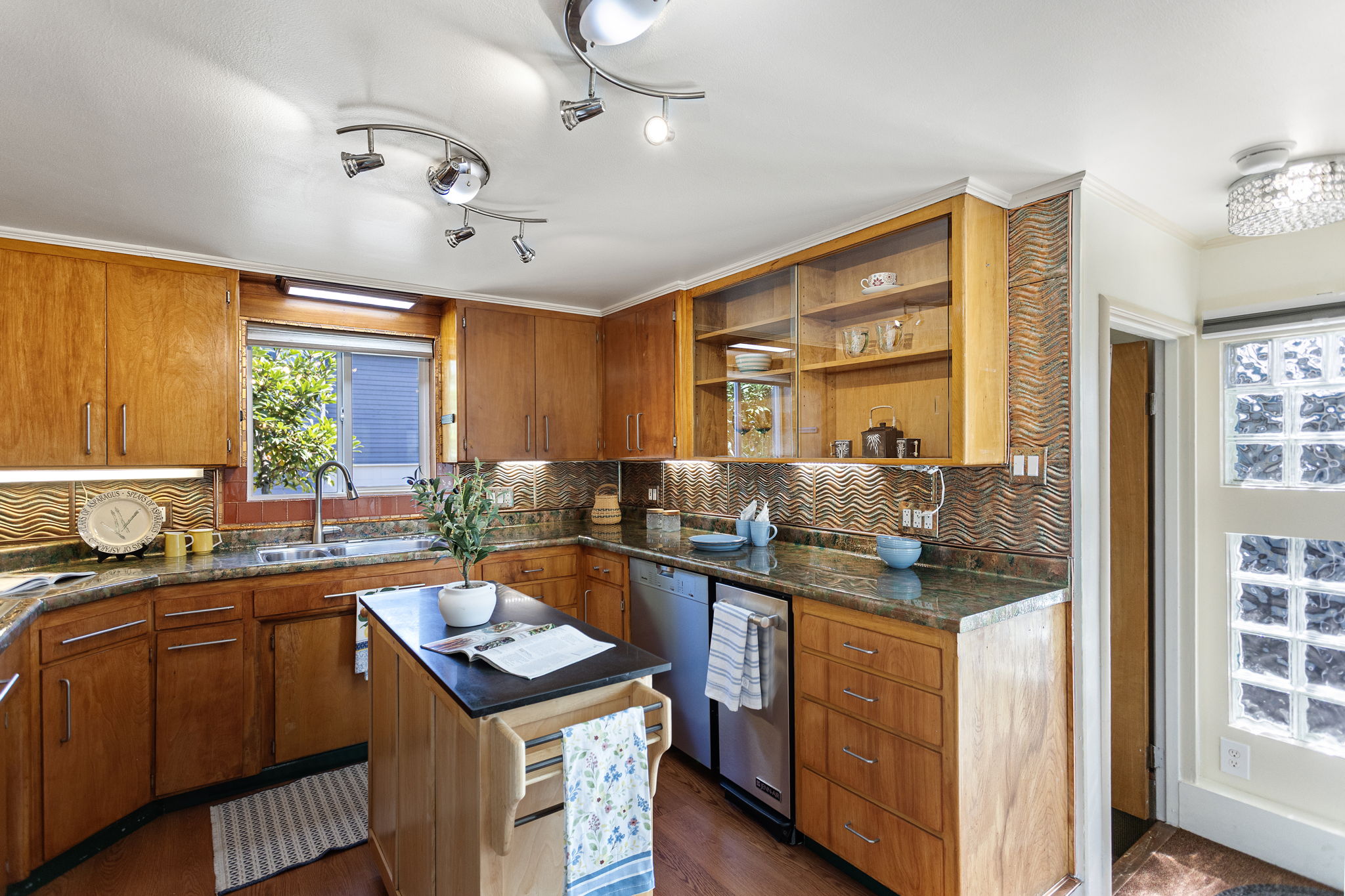 The kitchen wraps around three sides with abundant cabinetry, long stretches of counter space and a glass-front display cabinet that adds both storage and character.