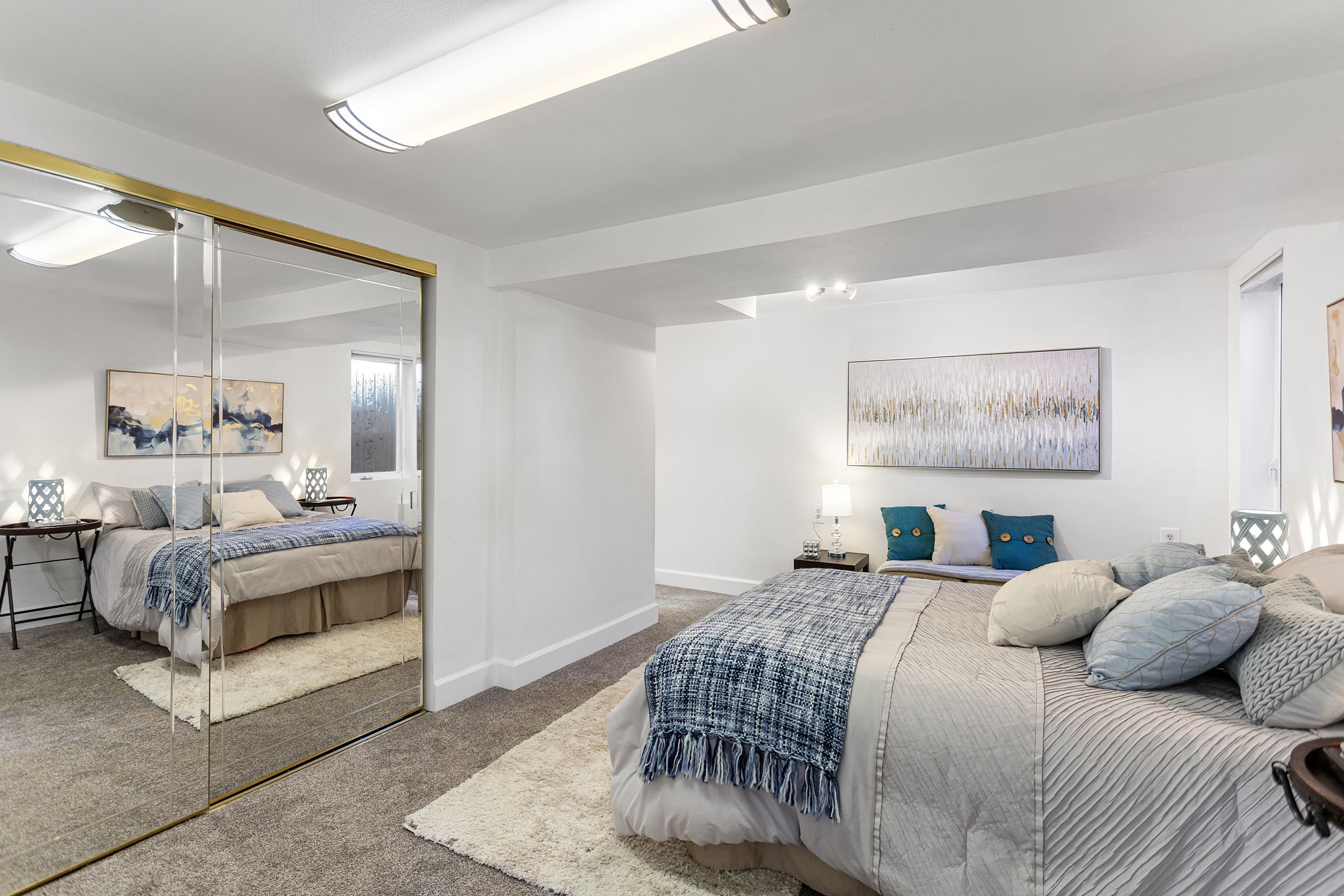 Generous closet storage spans the wall, with mirrored doors reflecting light across the bedroom.