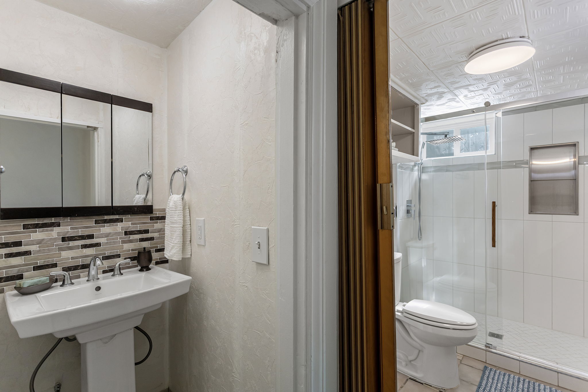The 3/4 bath is cleverly split into two spaces, with the pedestal sink separate from the roomy glass-enclosed shower and toilet area.