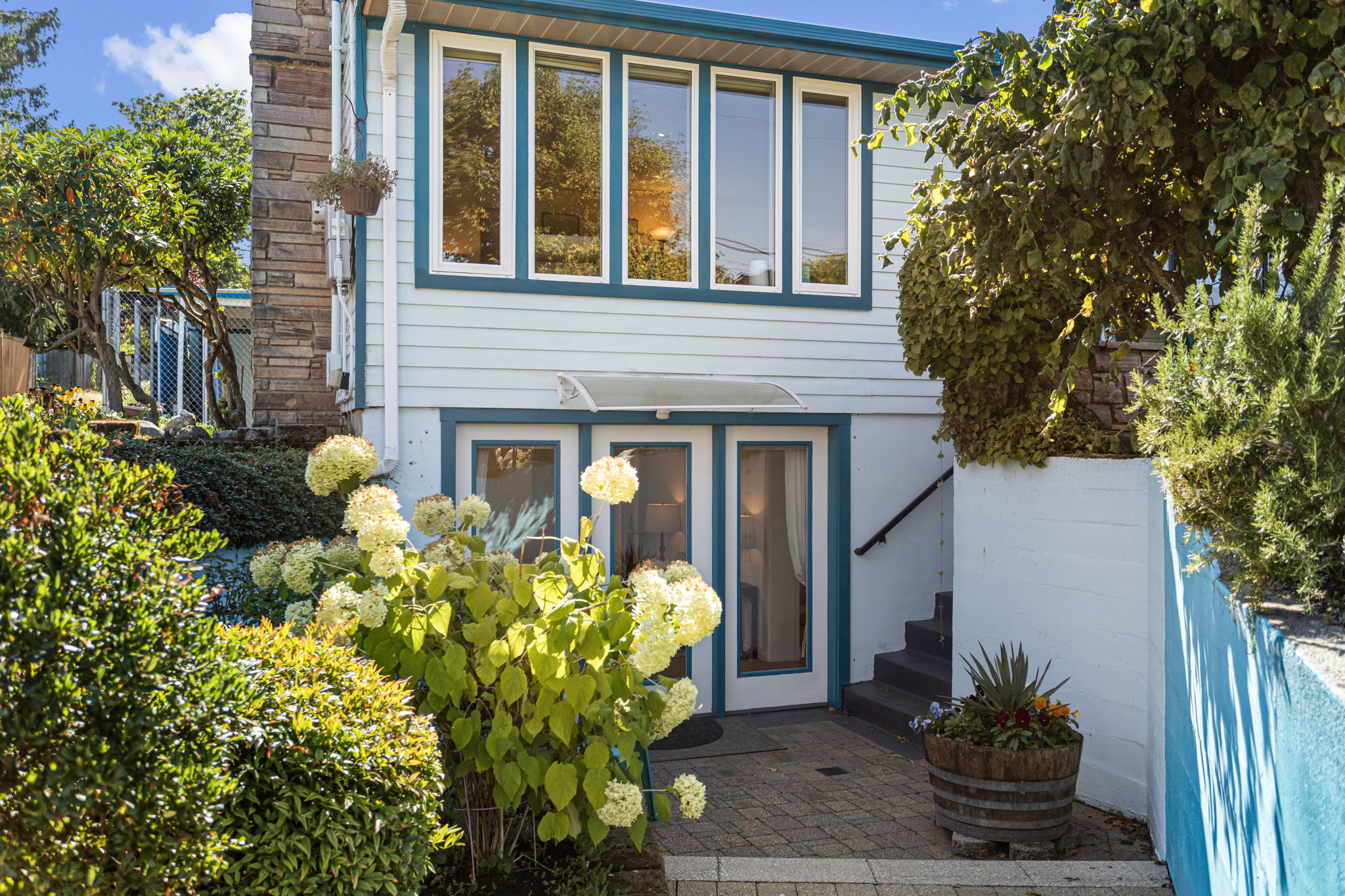 A beautifully hardscaped patio creates a private outdoor gathering area just outside the French-door entrance, reinforcing the separation from the main level.