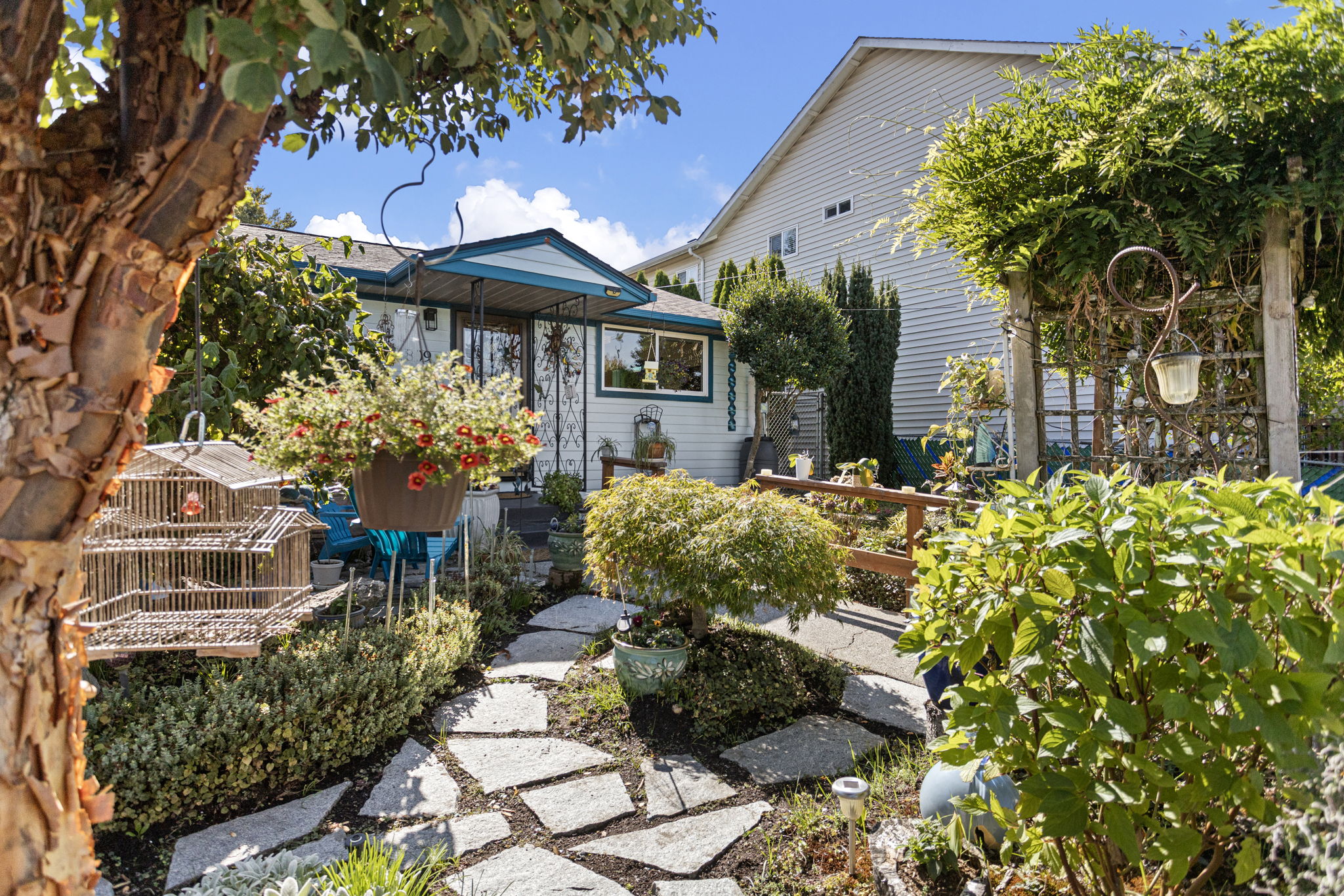 A Beacon Hill burst of joy: the front garden keeps changing as you move through it—slate underfoot, clipped shrubs, hanging blooms and bright color in every direction.