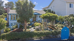 Garden. Gather. Belong. Behind the bright blue gate, mature plantings, arbors and garden art set the tone.