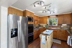 Stainless refrigerator, double wall ovens and a central work island add serious utility, while the east-facing window brings in morning light.