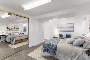 Generous closet storage spans the wall, with mirrored doors reflecting light across the bedroom.