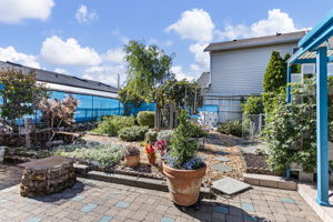 The garden story continues out back: grapevines, established beds, trellises, mature plantings, flowering pots and meandering paths create a second richly worked outdoor world.