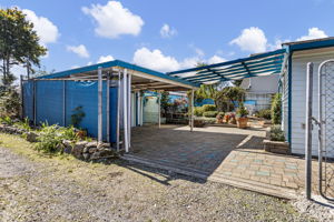 Off the alley, a remote-controlled automatic sliding gate secures the rear grounds and opens directly to the covered carport/patio.