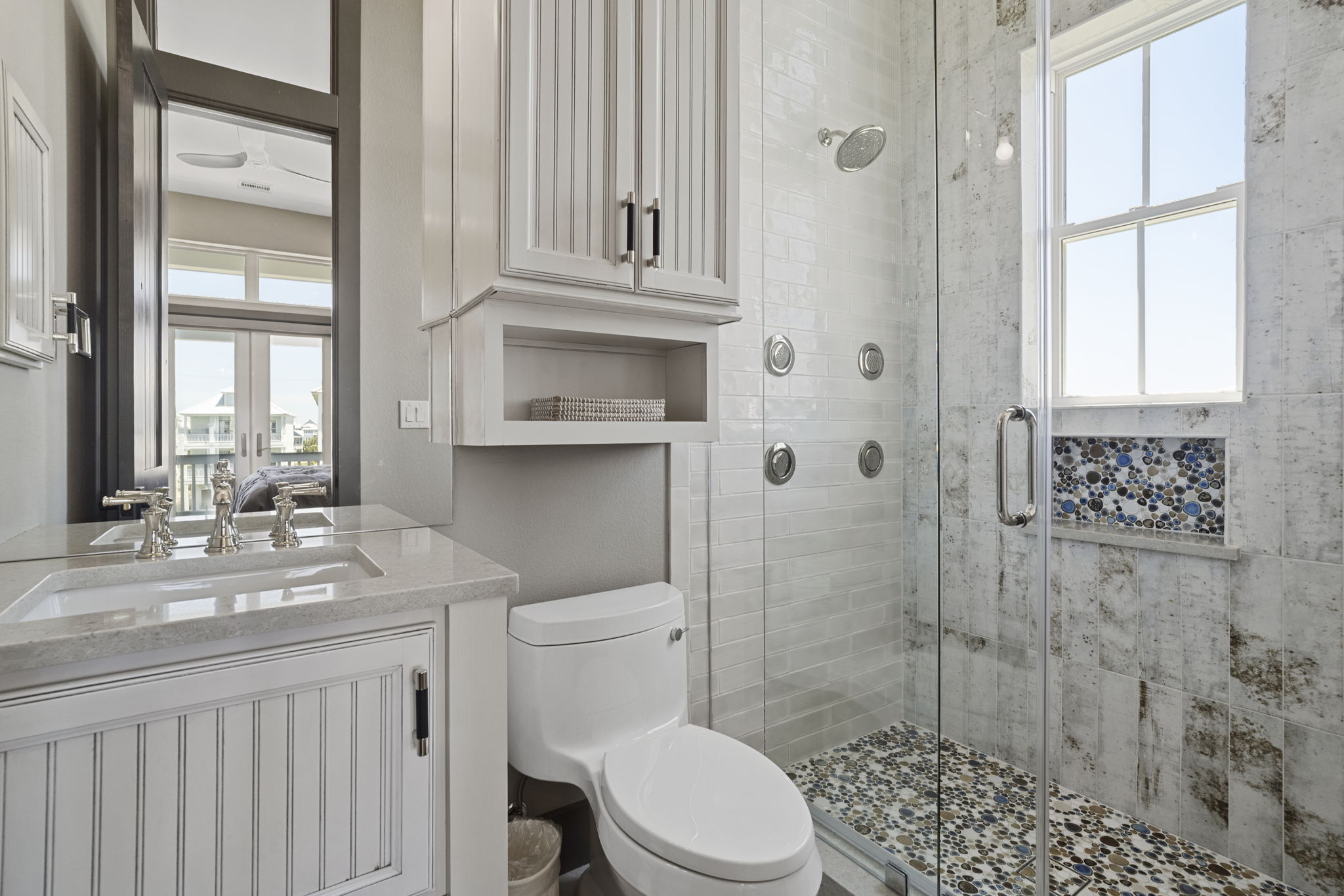 Shower has numerous options with shower heads and controls on adjacent walls.