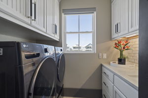 Full utility room w/ washer & dryer, sink, additional storage including a built in ironing board & broom & vacuum closet w/ power outlets inside!
