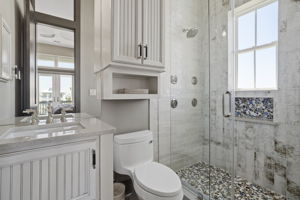Shower has numerous options with shower heads and controls on adjacent walls.