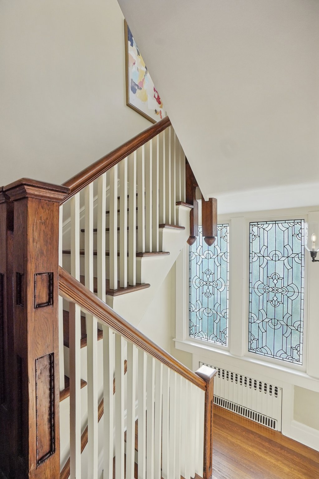 The original leaded glass window on the staircase catches the light just right—offering a subtle sparkle and a quiet nod to the home’s storied past.