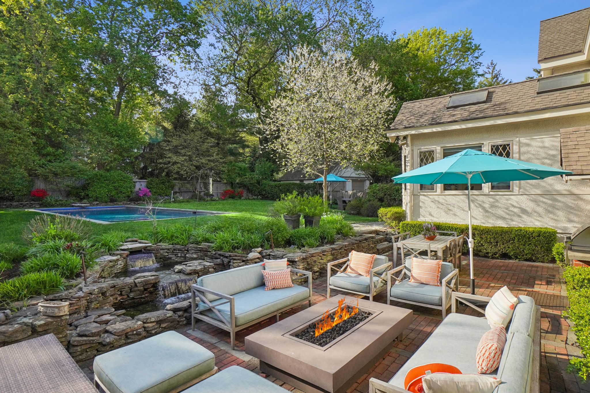 Resort-style outdoor living on a patio featuring a gas fed firepit and waterfall—ideal for lively gatherings or quiet relaxation under the stars.