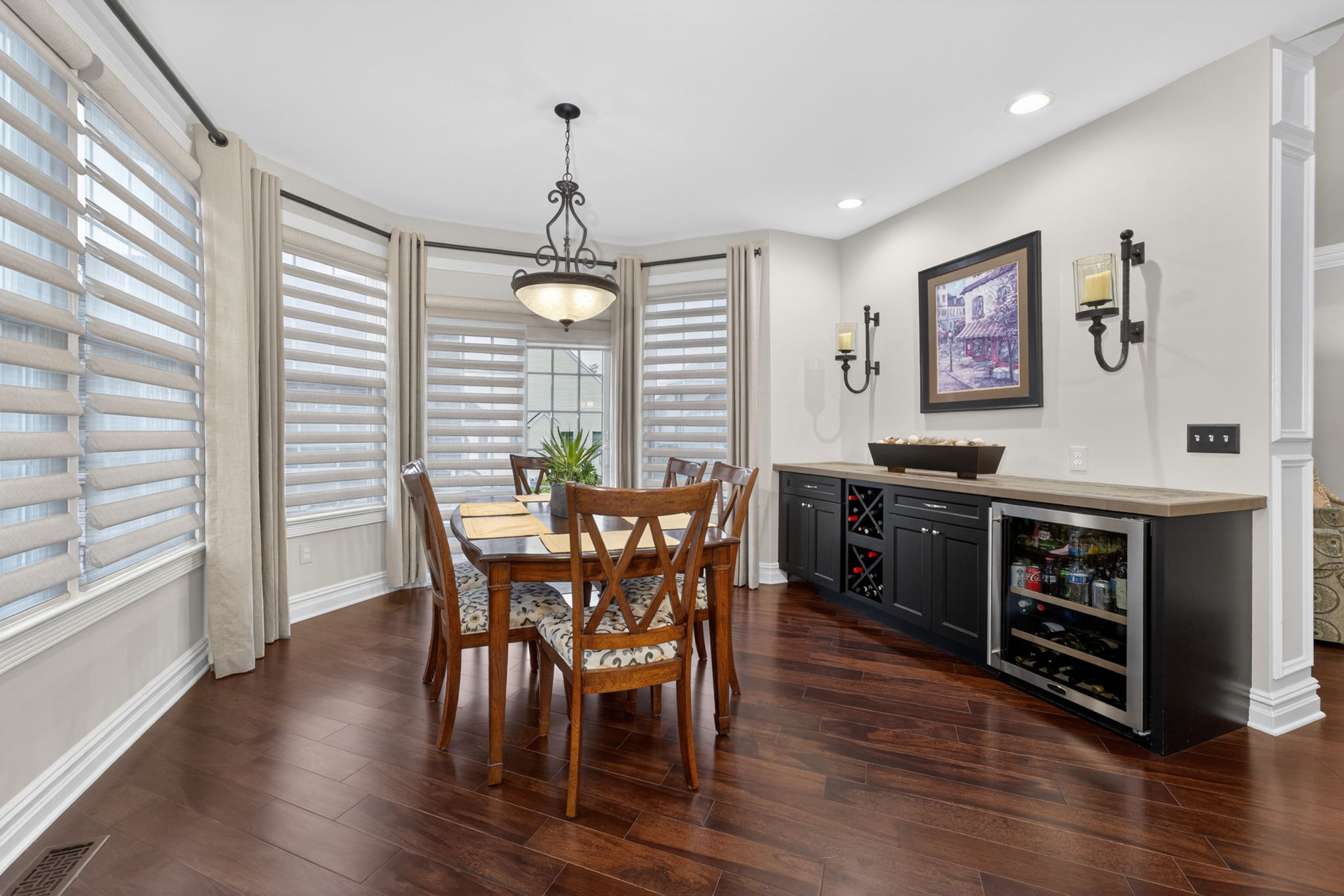 The casual dining nook features a built-in buffet with wine fridge, adding both style and convenience. A slider door opens to the expanded walled paver patio, creating a seamless transition for outdoor dining and relaxation.