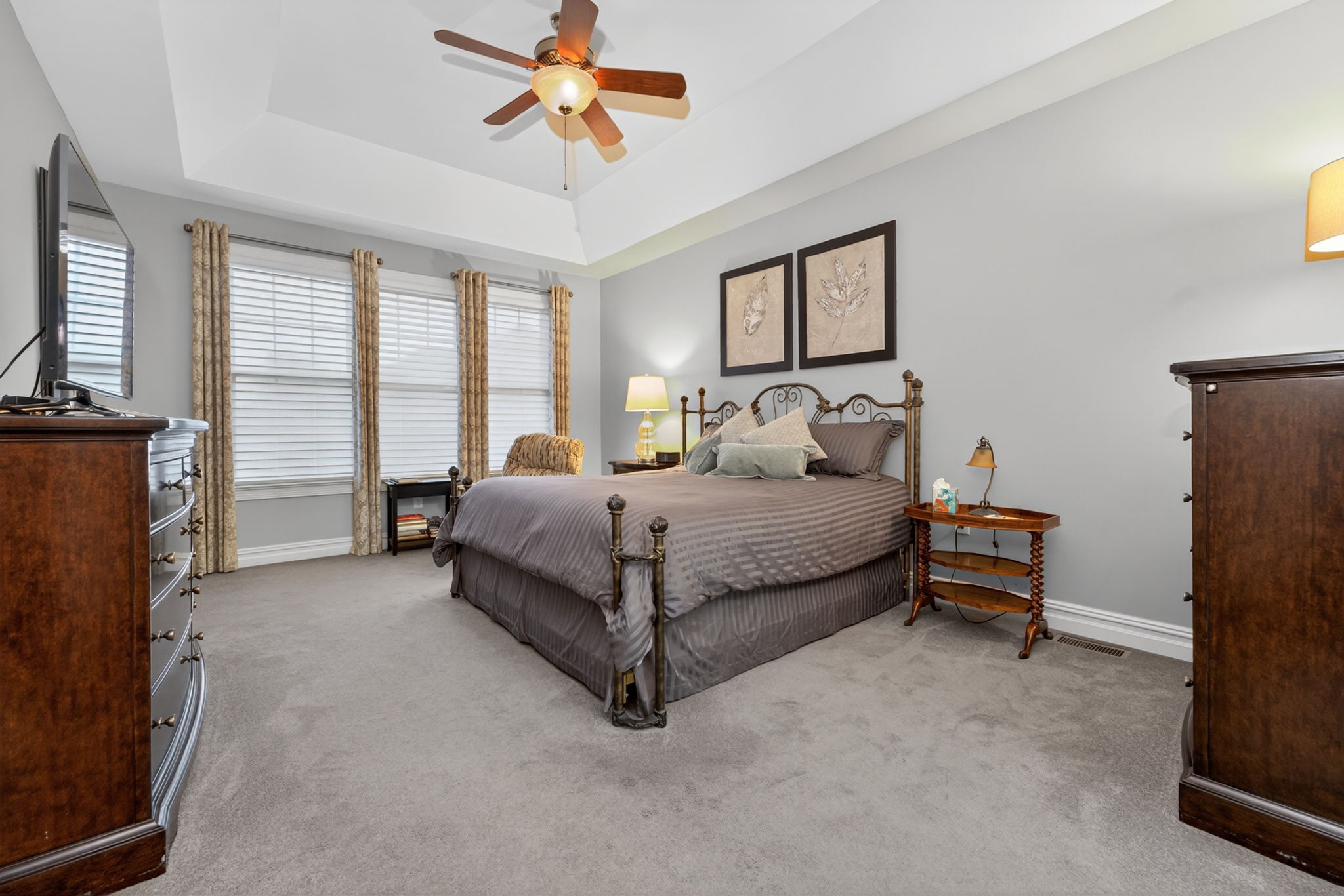 Primary Suite Features of the primary suite include a deep tray ceiling, ceiling fan, 2 walk in closets (1 with built-in organizer system), carpeting.