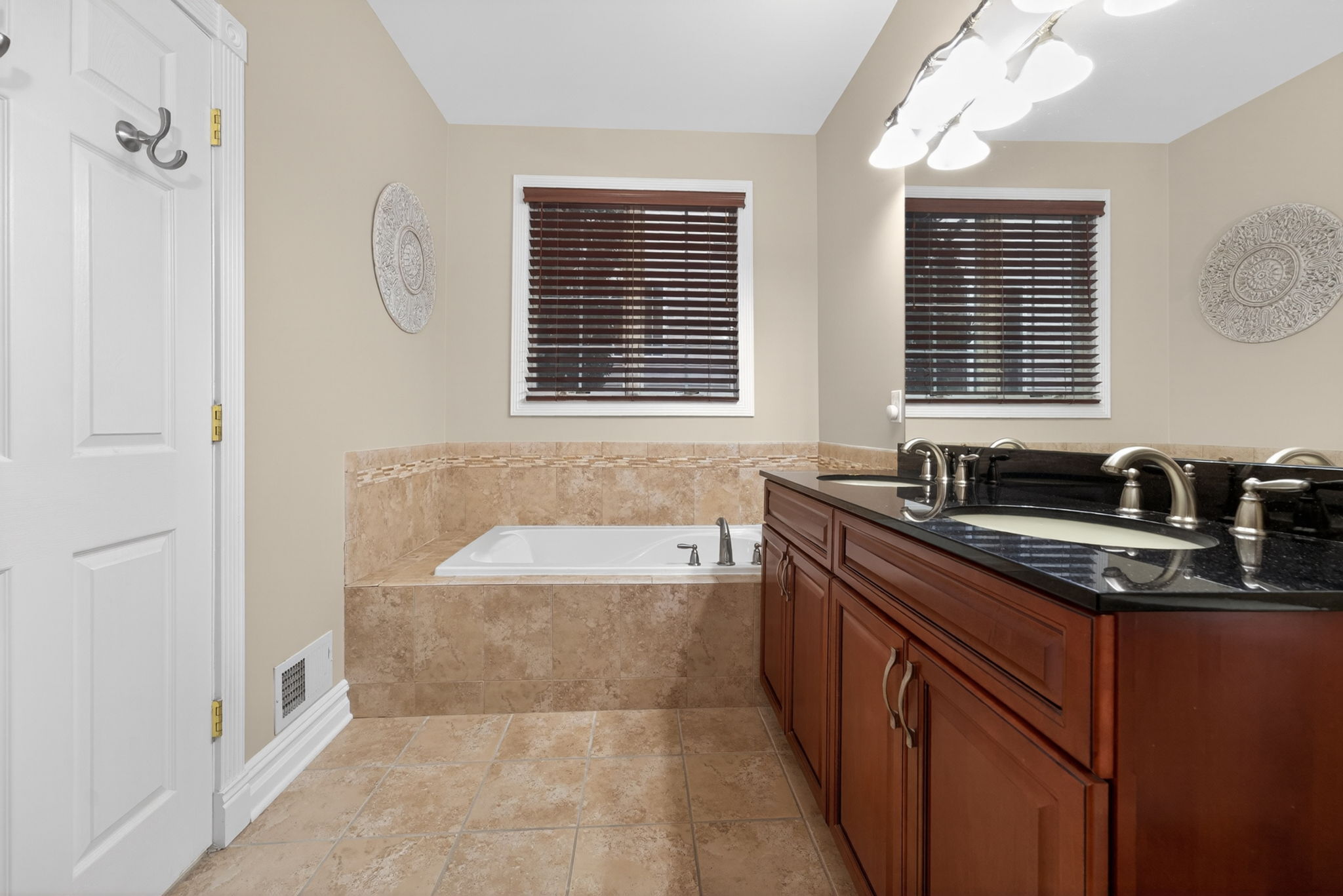 Relax and unwind in the luxurious en suite bath featuring a soaking tub, dual sinks set in a granite-top vanity, and an oversized tiled shower with pivot swing door and ceramic tile flooring.