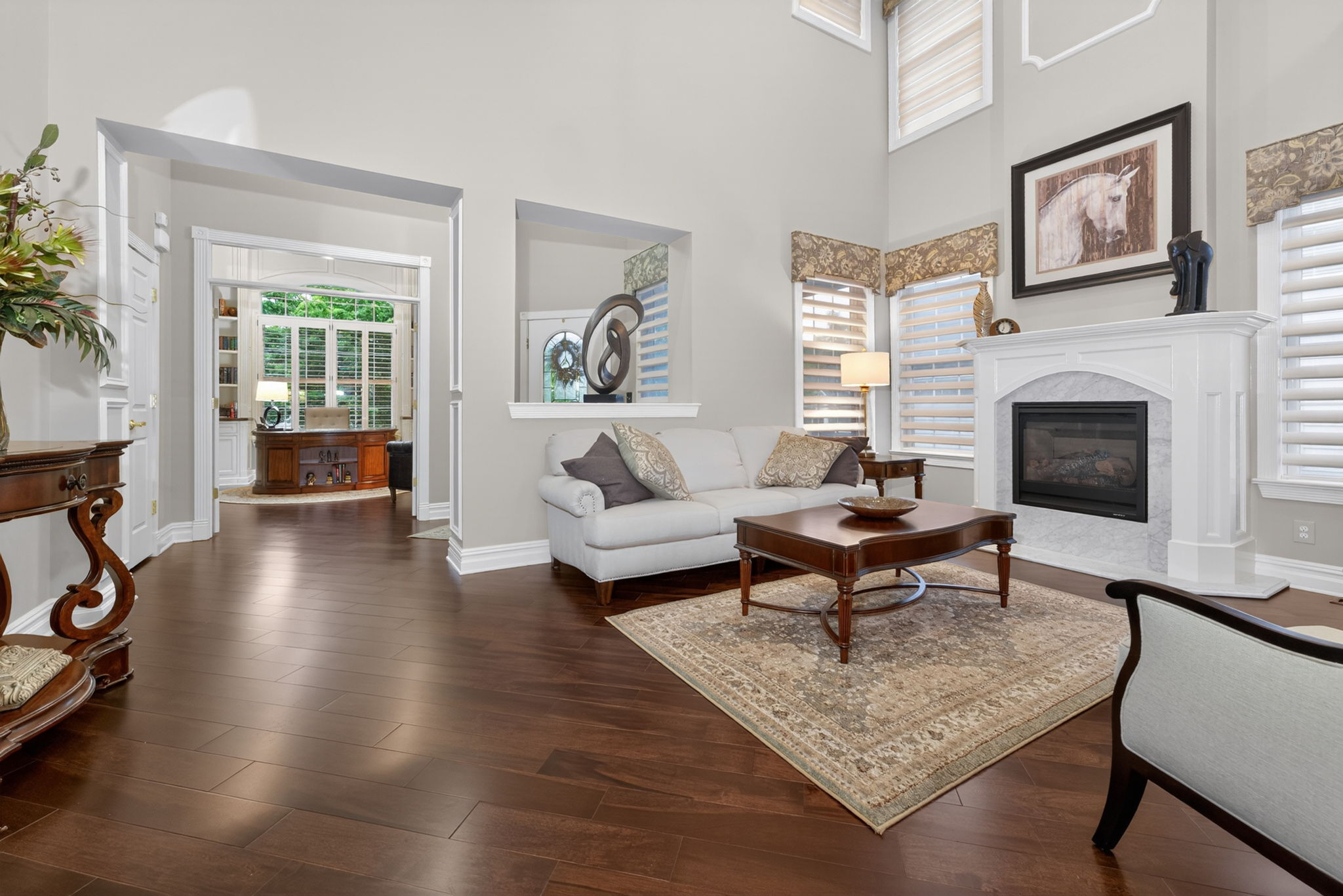 TWO STORY LIVING ROOM Two story living room features custom mouldings and wainscoting, 2 story windows, a gas fire-place with marble surround and custom mantel.