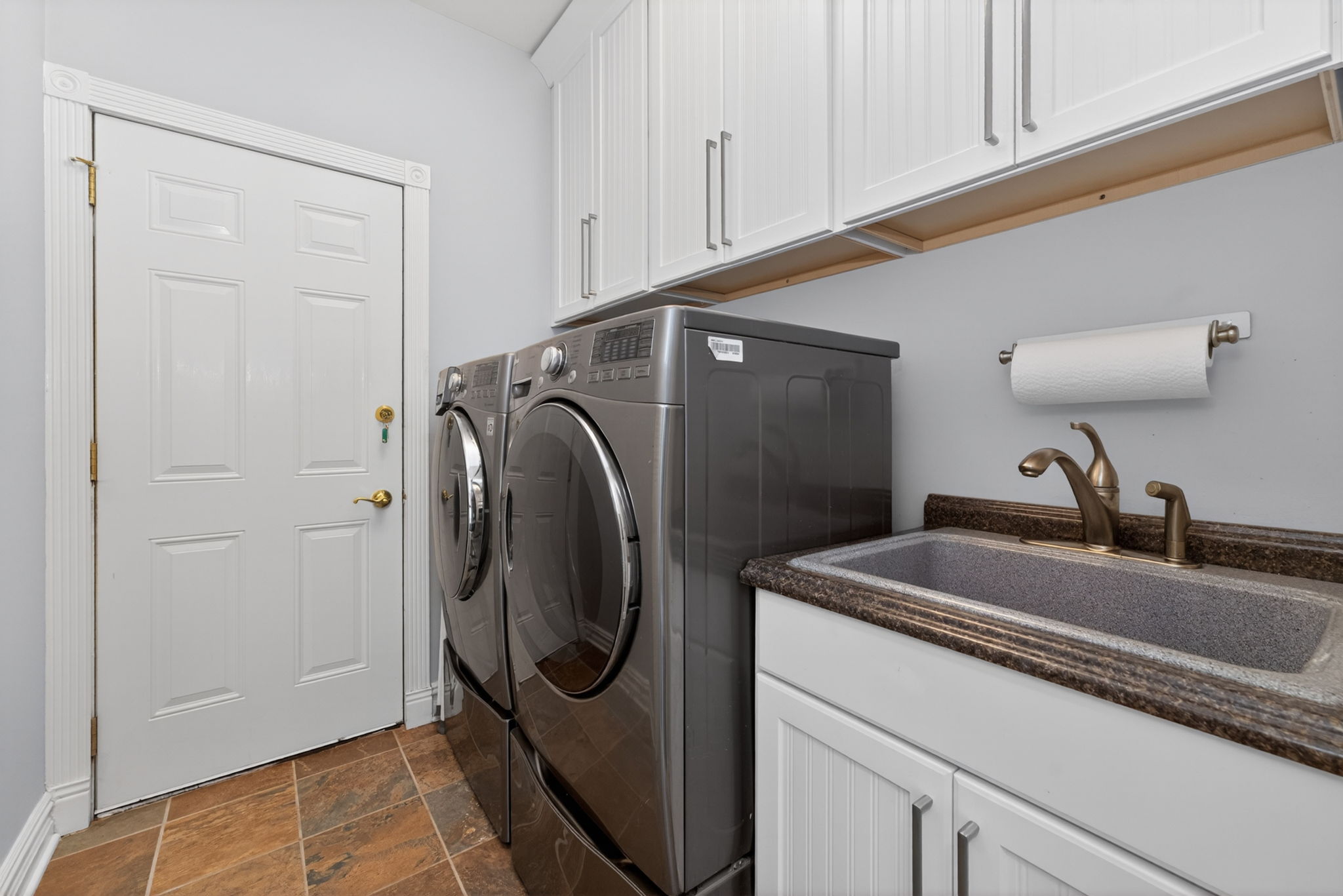 Laundrey Room-Level 1 Shaker style cabinetry, utility sink in cabinet, LG washer and dryer on pedestals, ceramic tile flooring, 2 car garage access.