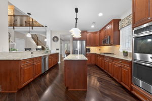 A center island prep station and separate granite breakfast bar with seating invite guests to gather and enjoy the cooking experience.