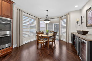 The casual dining nook features a built-in buffet with wine fridge, adding both style and convenience. A slider door opens to the expanded walled paver patio, creating a seamless transition for outdoor dining and relaxation.