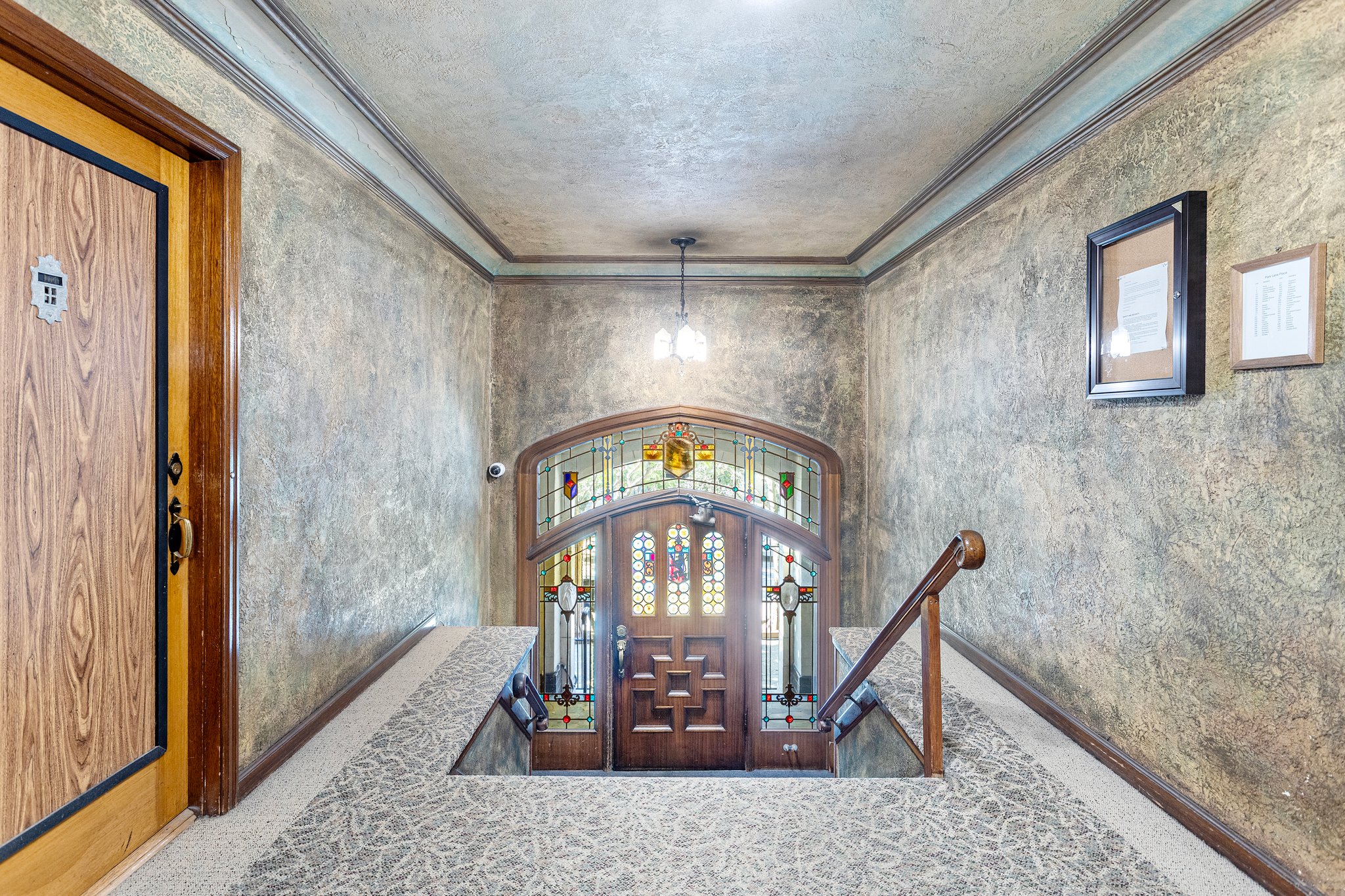 The inviting lobby exudes timeless elegance, with impeccably maintained millwork, stunning stained-glass Art Deco details, a cozy fireplace, and a classic gated elevator that whispers of a bygone era.