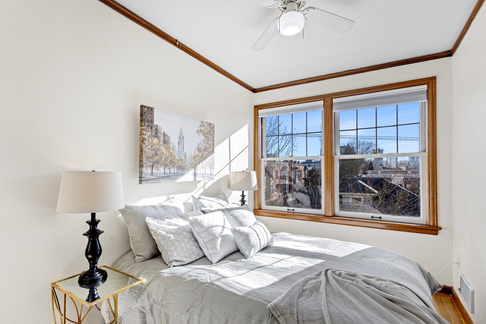 The cozy bedroom is bathed in natural light throughout the day, thanks to its wall-to-wall, south-facing window, offering serene city views and breathtaking sunsets to unwind by.