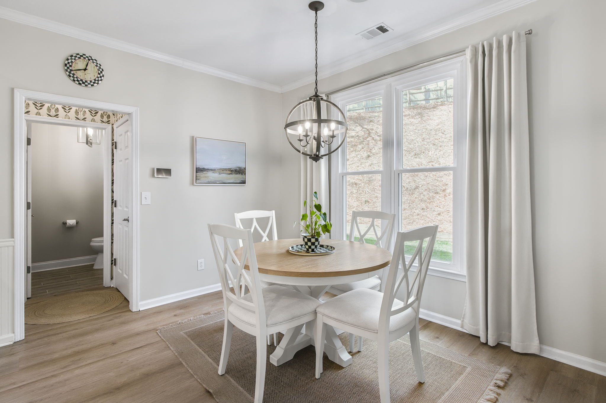 The breakfast nook is bathed in natural light from oversized windows, offering a peaceful setting for everyday meals. A stylish chandelier adds the perfect finishing touch.