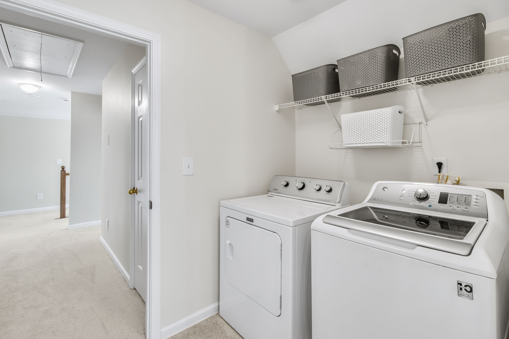 Spacious laundry room with overhead shelving for extra storage.