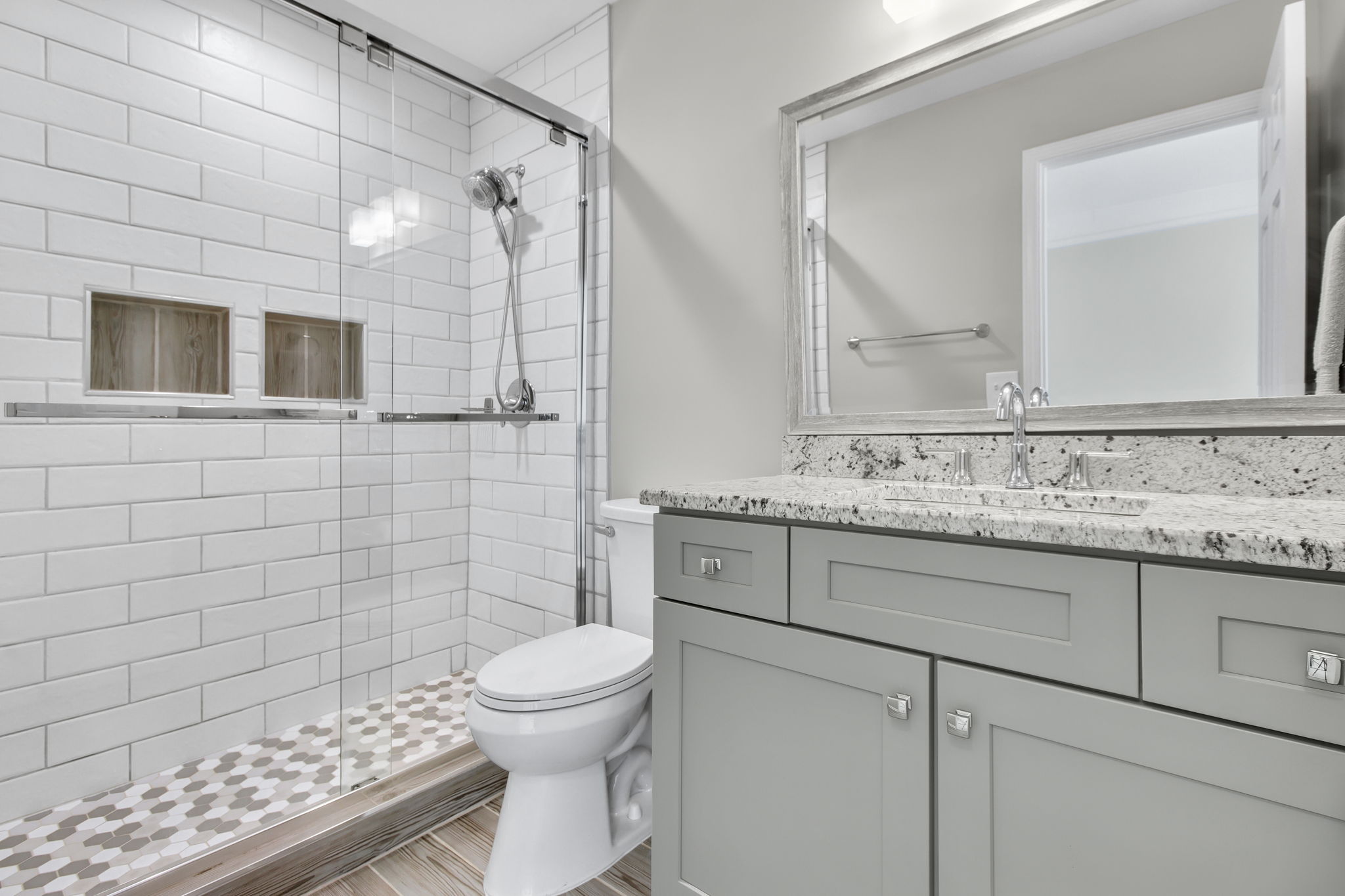 Stylish bathroom with a subway tile shower, elegant cabinetry, and granite countertops.