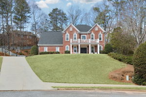 This stunning brick-front home sits atop a beautifully landscaped hill, offering timeless curb appeal with a spacious front porch and a grand entryway.