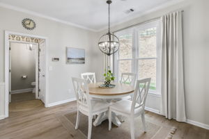 The breakfast nook is bathed in natural light from oversized windows, offering a peaceful setting for everyday meals. A stylish chandelier adds the perfect finishing touch.