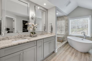 Designer Primary Bathroom – Featuring a deep soaking tub, vaulted ceiling, and a window.