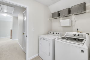 Spacious laundry room with overhead shelving for extra storage.