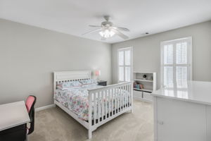 Bright and airy secondary bedroom with large windows and custom shutters.