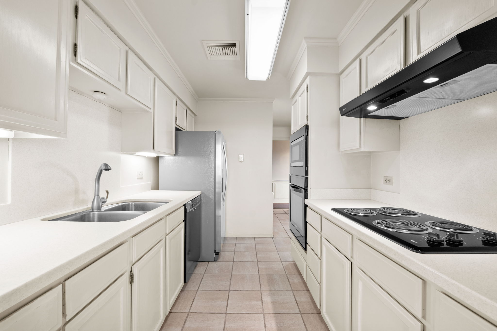 A fully appointed, pristine kitchen with abundant storage, solid surface counters, built-in oven and microwave, and walk-in pantry